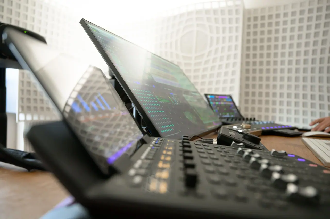 Detail of the mixing desk: control surfaces and screens showing an immersive session in progress.